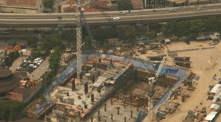 Construction site with cranes and buildings under development, representing infrastructure and civil works