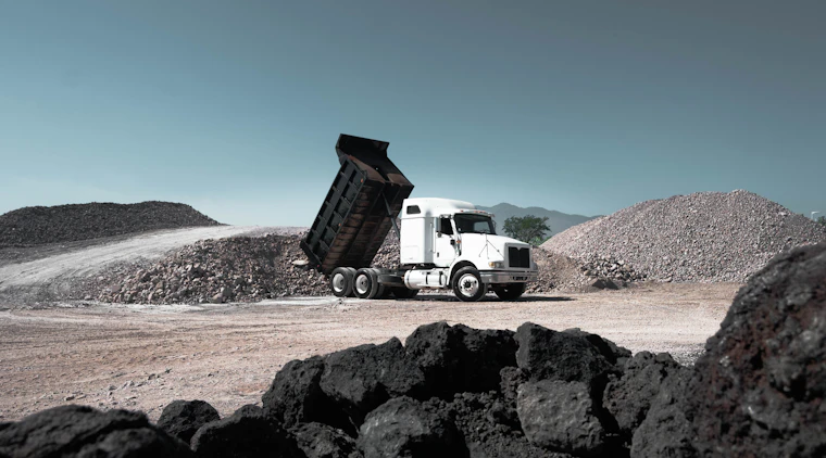 Dump truck unloading aggregate material at a quarry, representing mining and aggregates support
